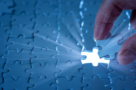 Hand setting final puzzle piece, light shining to emphasize completion of puzzle