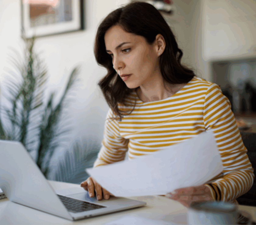 Woman at desk with hand written form typing into computer